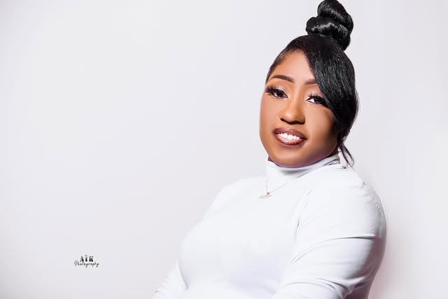 Woman in a white turtleneck smiling against a white studio background.